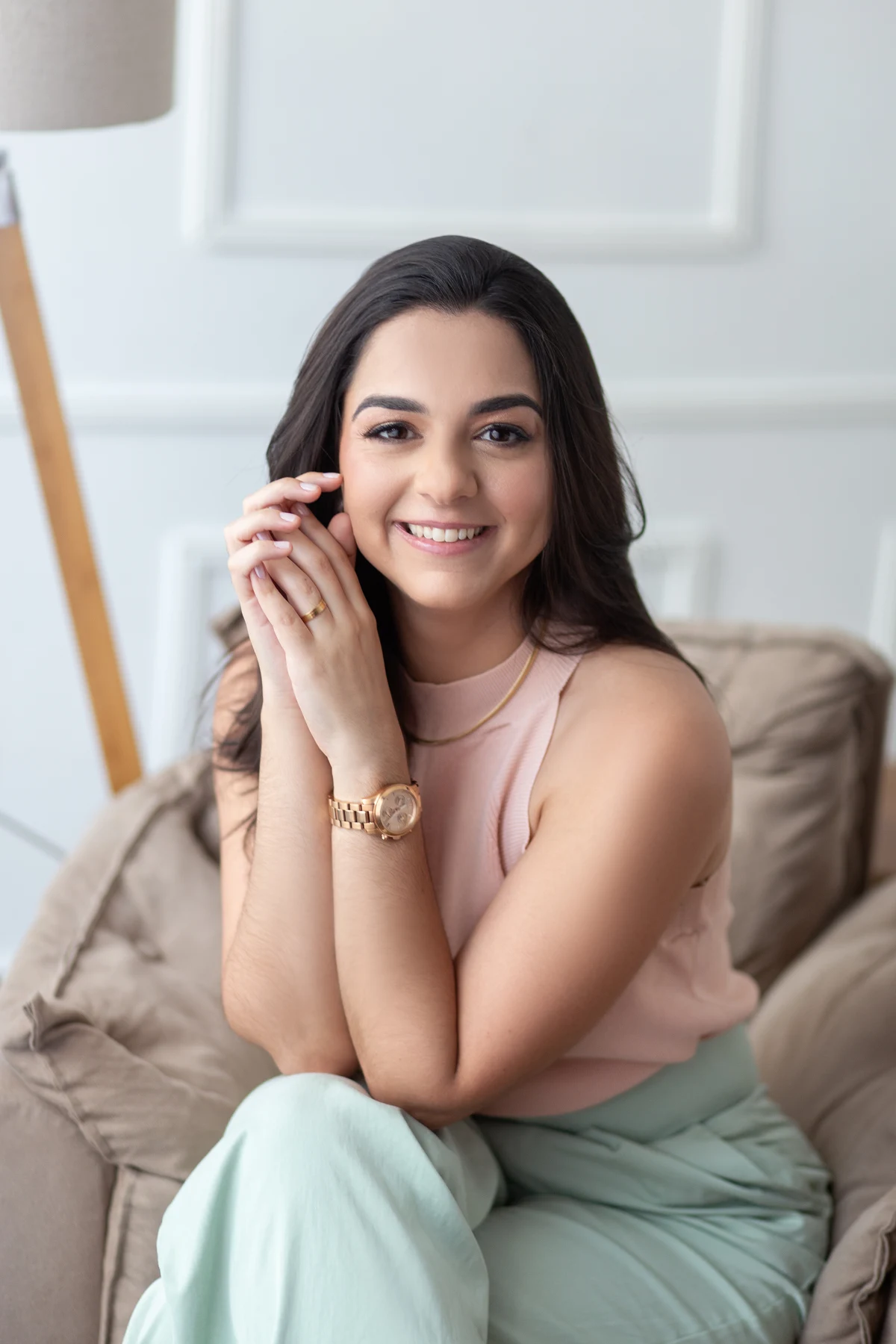Dra. Thamiris Auad sorrindo, sentada no sofá